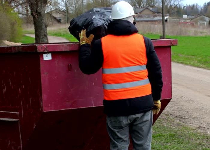 worker keeps garbage bag on waste container and talking